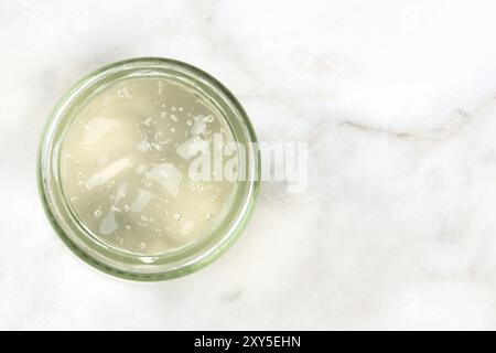 Une photo prise à la verticale d'un bocal en verre à l'aloe vera gel sur un arrière-plan en marbre blanc avec une place pour le texte Banque D'Images