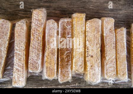 Miel avec des nids d'abeilles emballés dans des enveloppes en plastique sur une table en bois Banque D'Images