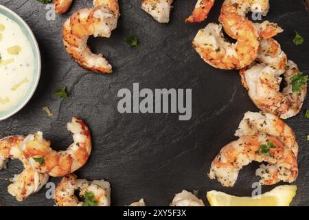 Crevettes frites avec une sauce caesar et citron, tourné par le haut sur un fond noir, formant une trame pour copy space Banque D'Images