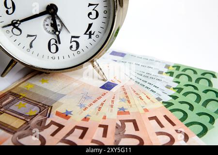 Billets en euros avec une vieille horloge mécanique, le temps c'est de l'argent Banque D'Images