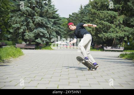 Patineur-adolescent aux cheveux longs dans un T-shirt et casquette de baskets saute l'ollie sur fond d'un ciel orageux à travers la ville Banque D'Images