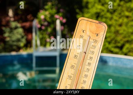 Thermomètre montrant près de 40 degrés celsius tenu au-dessus d'une piscine Banque D'Images