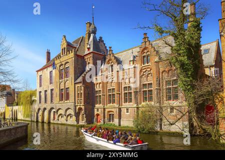 Bruges, Belgique, 10 avril 2016 : paysage urbain pittoresque avec des maisons médiévales, bateau avec des touristes et canal à Bruges, Europe Banque D'Images