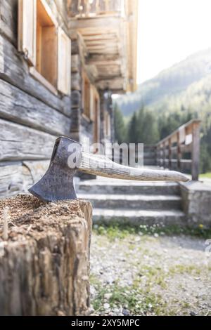 Vieille ax attaché à un tronc d'arbre, alpine hut Banque D'Images