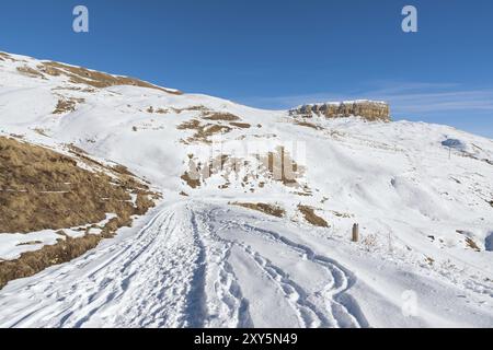 Le paysage de rochers caucasiens enneigés sur le col de Gumbashi. Plateau enneigé passant dans la montagne de la table avec un sentier de neige à l'avant Banque D'Images