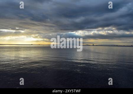 Mer calme rencontrant un ciel nuageux à l'horizon pendant le coucher du soleil Banque D'Images