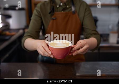 Barista au service du client donnant un cappuccino ou un latte fraîchement préparé Banque D'Images
