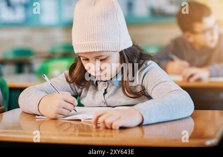 Enfant, fille et examen avec écriture, cahier d'exercices et bureau pour l'apprentissage, l'éducation et la croissance dans la leçon. Étudiant, connaissances et salle de classe pour l'étude Banque D'Images