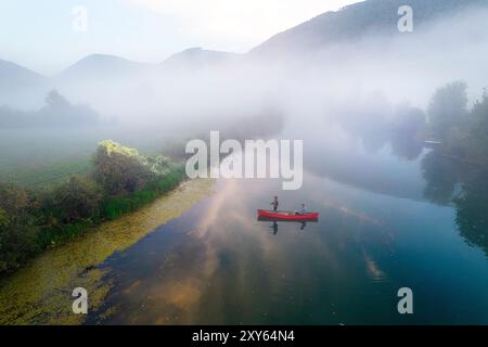 Vue aérienne d'un touriste, père et fils, pêche d'un canoë, bateau, sur un beau matin brumeux sur une rivière Krka dans la région de Dolenjska, Slovénie Banque D'Images