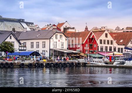 Stavanger, Norvège, 2 août 2018 : vue sur la rue de la ville avec des gens, un café, des restaurants et des maisons en bois traditionnelles colorées à la promenade près du port, E. Banque D'Images