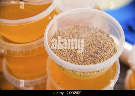 Les granules de pollen d'abeille dans un bocal en plastique debout sur des bocaux de miel sont vendus à l'extérieur Banque D'Images