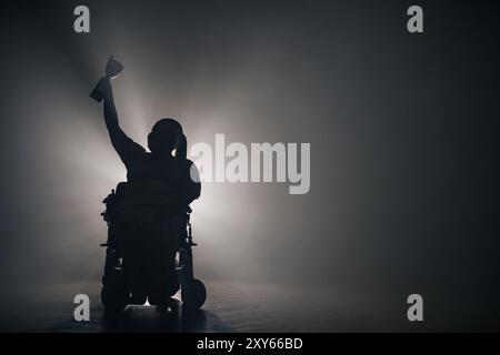 Femme handicapée recevant une coupe de victoire alors qu'elle était assise dans un fauteuil roulant dans une pièce sombre avec un rétroéclairage blanc. Banque D'Images