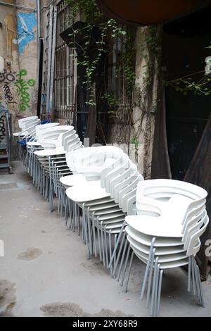 Chaises blanches empilées dans une cour arrière à Berlin Banque D'Images