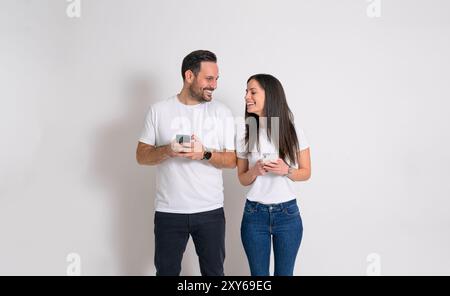 Femme ludique jetant un coup d'œil au téléphone intelligent de petit ami et essayant de lire ses messages sur fond blanc Banque D'Images