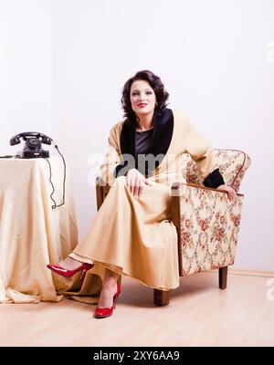 Femme habillée dans le style des années cinquante dans une robe de chambre jaune Banque D'Images