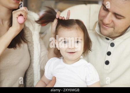 Les parents se peigner les cheveux de bébé ils Banque D'Images