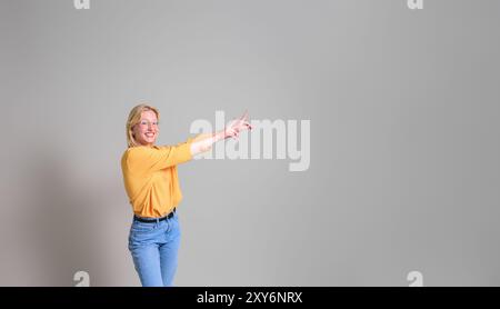 Vendeuse souriante avec les bras levés pointant vers le nouveau produit et le marketing sur fond blanc Banque D'Images