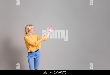 Heureuse jeune femme d'affaires montrant et annonçant le nouveau produit tout en se tenant sur fond blanc Banque D'Images