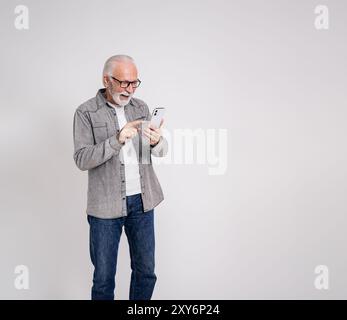 Homme d'affaires senior excité lisant de bonnes nouvelles sur téléphone intelligent et riant sur fond blanc Banque D'Images