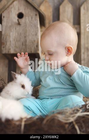 Little baby girl avec un petit lapin blanc sur le fond de bois Banque D'Images