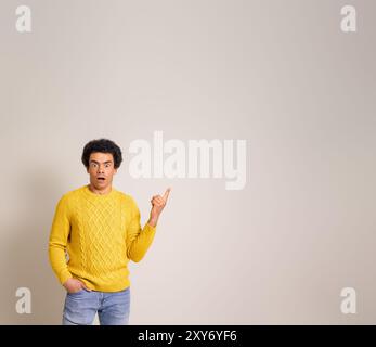 Portrait de jeune homme d'affaires choqué pointant à l'espace de copie et la publicité sur fond blanc Banque D'Images