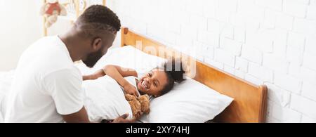 Père et fille appréciant le matin confortable ensemble dans la chambre lumineuse Banque D'Images