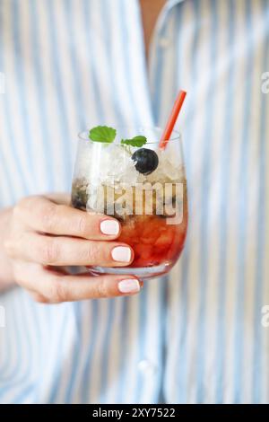 Cocktail de glace myrtille décoré par mint dans la main d'une femme Banque D'Images