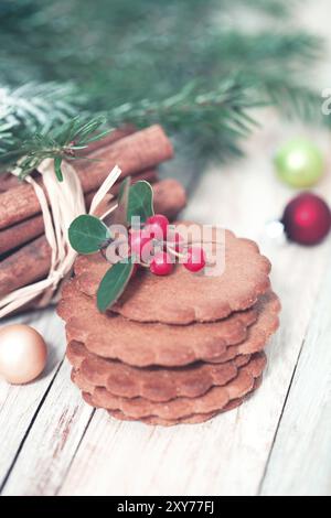 Pile de biscuits traditionnels en pain d'épices diverses placés sur une table en bois blanc près des branches de conifères le jour de Noël Banque D'Images