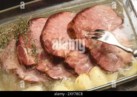 Porc fumé avec oignon dans une casserole. Dîner, longe. Tranches de porc fumé dans une poêle en verre Banque D'Images