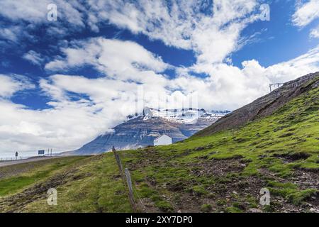 Hangar blanc avec un toit rouge devant les montagnes enneigées sur l'Islande Banque D'Images