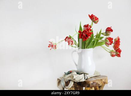 Nature morte au bouquet de tulipes dans un vase blanc en bois chaise rustique sur Banque D'Images