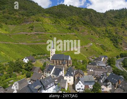 Un petit village avec une église entourée de vignes et de collines verdoyantes sous un ciel bleu avec des nuages, vue aérienne, Bremm, vignobles du Calmont, un Banque D'Images