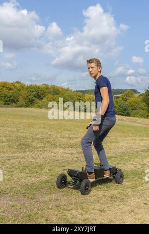 Jeune homme européen rides mountainboard électrique offroad Banque D'Images