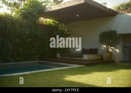 Salon extérieur près de la piscine avec lits, jardin vertical, zone herbeuse et piscine privée dans une villa de luxe Banque D'Images