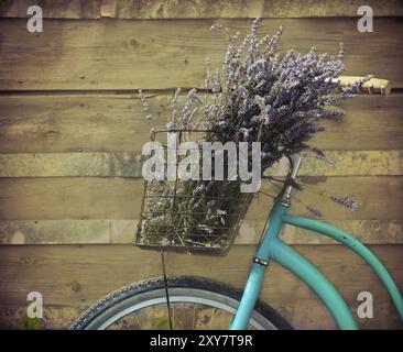 Vélo Vintage avec panier avec des fleurs de lavande près du mur en bois Banque D'Images