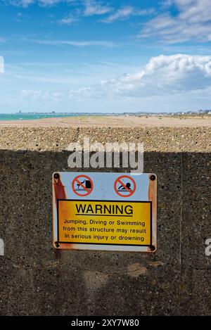 Un avis d'avertissement sur un brise-lames au port de Shoreham sur les dangers de sauter la plongée ou la natation de cette structure West Sussex England UK Banque D'Images