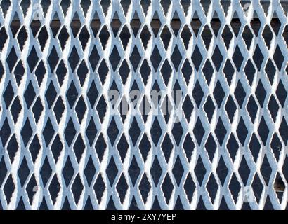 Un plancher de grille en métal crée un joli fond ou motif de texture avec des triangles courbes. Banque D'Images