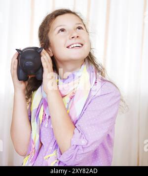 Petite fille économisant de l'argent dans une tirelire. Portrait en intérieur Banque D'Images