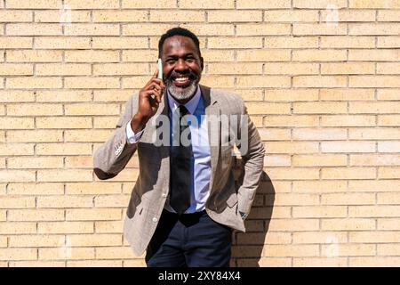 Homme d'affaires noir mature portant costume élégant se promenant dans la ville - homme senior adulte africain corporatif avec barbe grise Banque D'Images