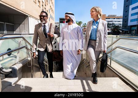 Groupe de gens d'affaires multiethniques rencontrant un homme d'affaires émirati - équipe d'affaires internationale liant à l'extérieur dans la ville et Travellin Banque D'Images