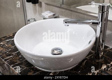 Lavabo et vanité dans une salle de bains principale d'une nouvelle maison haut de gamme. Photo d'intérieur d'une vanité de salle de bains de style moderne avec banc en dalle de marbre. Robinet avec w Banque D'Images