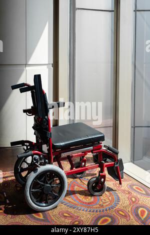 Fauteuil roulant vide près de la fenêtre à l'aéroport pour le service pour les personnes handicapées ou les passagers âgés. Fauteuil roulant pour personnes handicapées et maladie hospitalière dans Banque D'Images