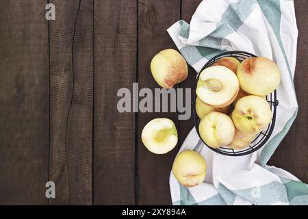 Plat avec de grandes et grandes pêches juteuses bio dans le panier en métal près de la serviette de cuisine sur fond de table en bois brun avec de vieilles planches. FRU naturelles Banque D'Images