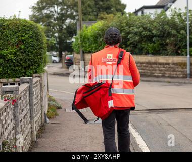 Un facteur effectue des livraisons dans le village de Northowram, dans le West Yorkshire, à Calderdale, au Royaume-Uni. Royal mail Group Limited, opérant sous le nom de Royal mail, est une société britannique de services postaux et de messagerie. Elle appartient à International distribution services. Elle exploite les marques Royal mail (lettres et colis) et Parcelforce Worldwide (colis). Crédit : Windmill images/Alamy Live News Banque D'Images