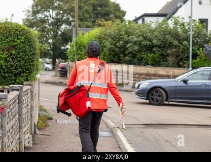 Un facteur effectue des livraisons dans le village de Northowram, dans le West Yorkshire, à Calderdale, au Royaume-Uni. Royal mail Group Limited, opérant sous le nom de Royal mail, est une société britannique de services postaux et de messagerie. Elle appartient à International distribution services. Elle exploite les marques Royal mail (lettres et colis) et Parcelforce Worldwide (colis). Crédit : Windmill images/Alamy Live News Banque D'Images