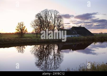 Maison de ferme néerlandaise par canal au coucher du soleil Banque D'Images