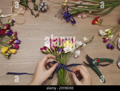 Un fleuriste au travail. Femme faisant bouquet de fleurs freesia printemps Banque D'Images