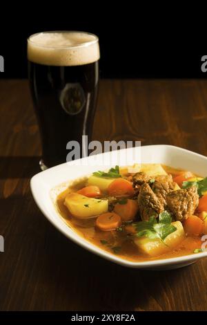 Ragoût irlandais traditionnel sur une assiette carrée avec une pinte de bière sur une table Banque D'Images