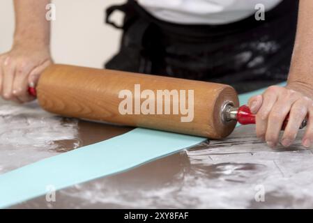 Confiseur utilisant un rouleau à pâtisserie préparant un fondant pour la décoration de gâteaux Banque D'Images