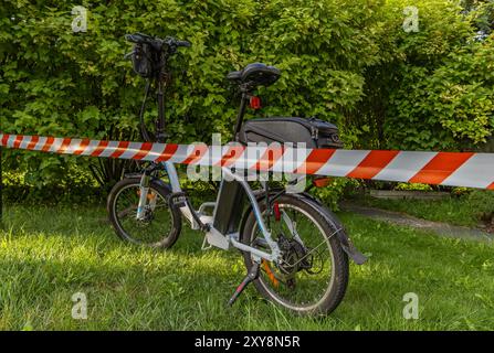 Un accident sur un vélo électrique, la zone sécurisée par la police avec du ruban protecteur rouge et blanc Banque D'Images